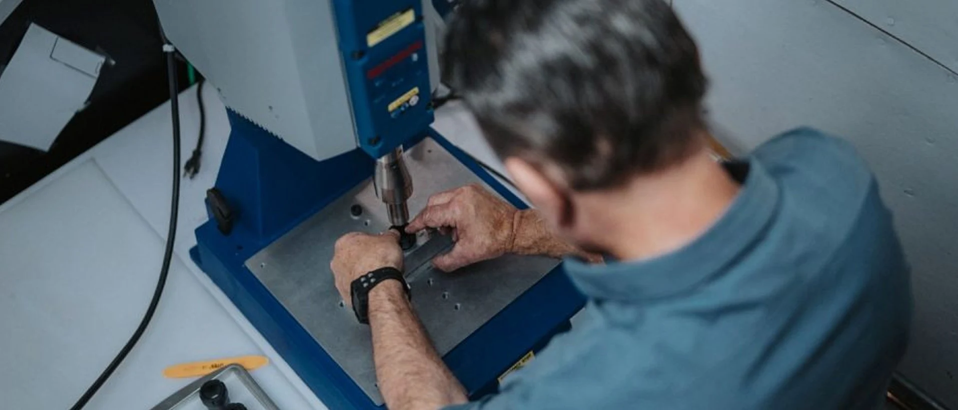 Technician performing ultrasonic insertion and ultrasonic welding on a plastic component
